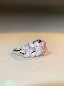 Macro view of radiant pink gemstone ring with marquise accent stones and silver hollow band