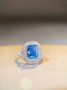 Macro shot of cushion-cut blue sapphire ring with double halo diamond setting in silver