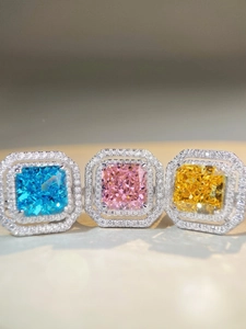 Detailed macro view of vibrant radiant-cut pink, blue, and yellow gemstone rings in halo setting