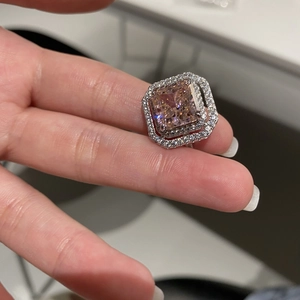 Macro detail of a square-cut pink zircon ring with double halo setting on finger