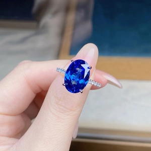 Detailed view of an oval blue sapphire ring with a four-prong setting and pavé side diamonds