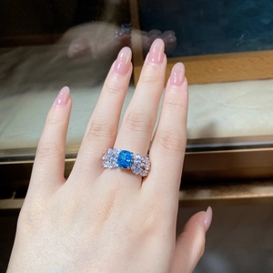Macro detail of aquamarine ring on finger featuring ice flower cut and zircon wings