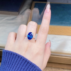 Detailed view of an oval blue sapphire ring with high carbon diamonds on hand