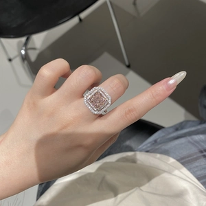 Close-up of a pink square-cut zircon ring with double halo and silver metal setting