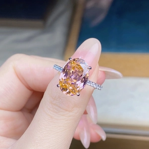 Detailed macro view of an oval pink sapphire ring with micro-pave diamond silver band