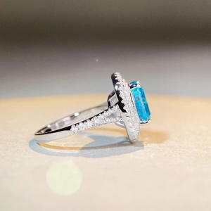 Macro shot of rectangular blue gemstone ring with double halo and diamond pavé band