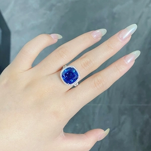 Bague saphir taille coussin avec halo de diamants et anneau pavé portée au doigt