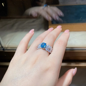 Detailed close-up of a large blue gemstone ring with leaf-shaped zircon side stones