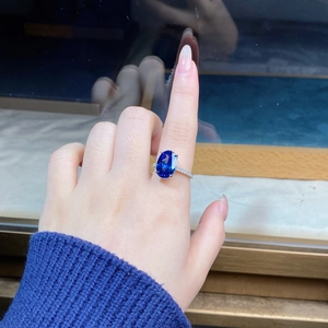 Detailed view of an oval blue sapphire ring in a silver four-prong diamond setting