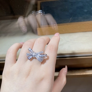Detailed close-up of a bow-knot ring with pave diamonds on a hand, sterling silver finish