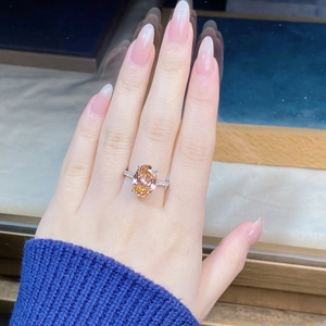 Macro shot of an oval champagne gemstone ring with a diamond-pave band on a finger
