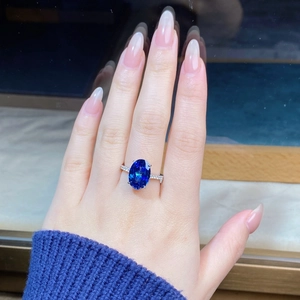 Macro shot of 6 carat oval blue gemstone ring with pave diamonds on silver band