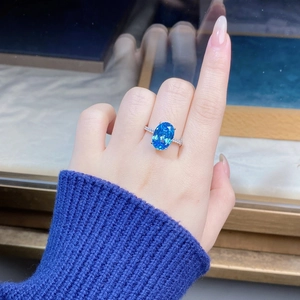 Close-up of an oval aquamarine ring on hand featuring a halo of sparkling zircons