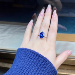 Close-up of 6-carat oval blue sapphire ring with pavé diamond setting on woman's finger
