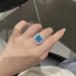 Close-up of aquamarine ring with radiant cut and double halo on finger