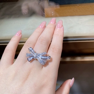 Macro view of a shimmering bow-shaped silver ring with micro-paved zircons on a hand