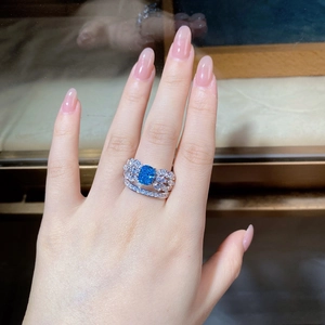 Close-up of aquamarine blue gemstone ring with zircon pavé butterfly wings on hand