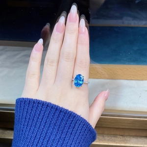 Detailed view of an oval blue gemstone ring with pave diamonds on a silver band