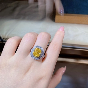 Detailed close-up of a luxury silver ring with yellow gemstone and double halo diamonds