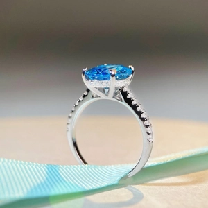 S925 sterling silver ring with oval aquamarine and side diamonds on a blue ribbon