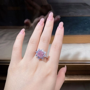 Detail of flower-shaped ring with pink square gem and white diamonds on a hand