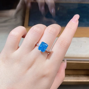 Macro view of a large rectangular blue zircon ring with trapezoid side stones on hand