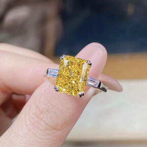 Makroaufnahme eines Drei-Stein-Rings mit gelbem Edelstein und Diamanten im Baguetteschliff