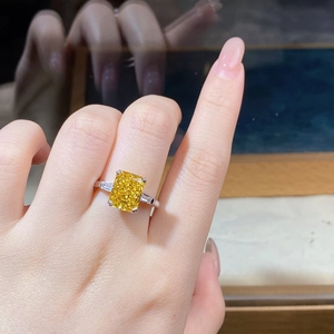 Detailaufnahme eines Rings mit großem gelben Edelstein am Finger einer Frau