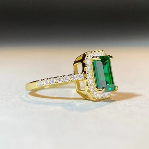 Macro side view of 18K gold plated silver ring with emerald cut green stone and diamonds