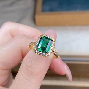 Macro shot of 925 silver emerald cut ring with 18K gold plating and halo diamond setting