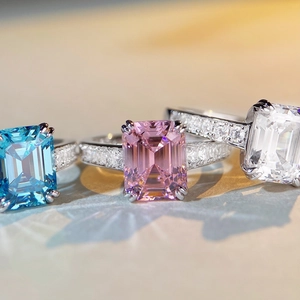 Macro detail of emerald-cut rings in pink, blue, and clear with pave diamond bands