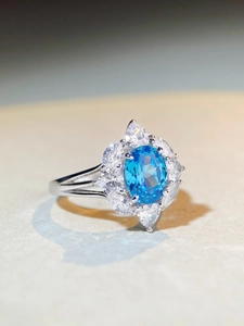 Close-up of S925 silver ring featuring an oval blue gemstone with a floral halo design