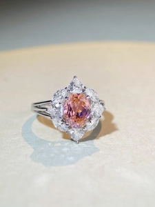 Close-up of S925 silver flower ring with oval pink-orange gem and marquise zircons