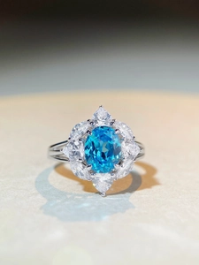 Macro shot of S925 silver ring featuring an oval blue gemstone and flower zircon petals