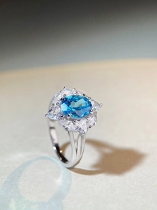 Top view of oval blue gemstone ring with floral clear zircon cluster setting