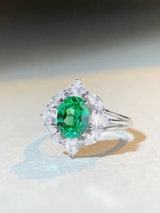 Macro shot of S925 silver ring featuring an oval green gemstone and floral halo setting