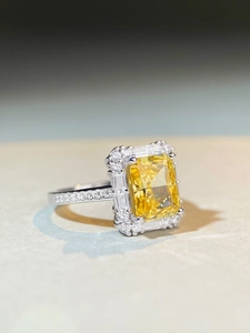 Macro view of a rectangular yellow gemstone ring with a double diamond halo and pave band