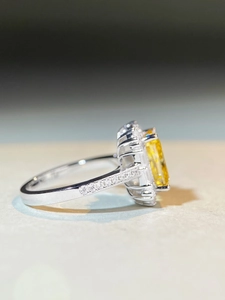 Detailed side view of silver ring showing princess cut yellow stone and halo setting