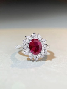Macro detail of oval ruby ring with marquise-cut diamond halo and pavé setting