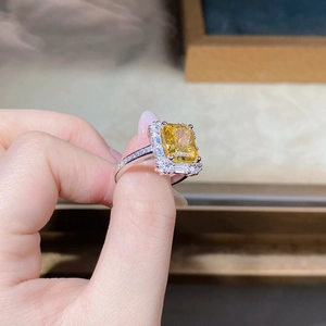 Macro detail of emerald-cut yellow zircon ring with silver halo and pavé setting