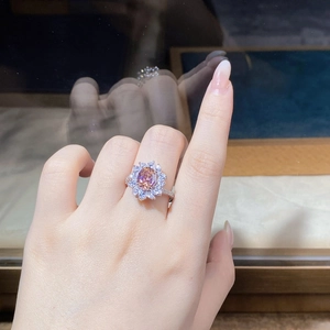 Close-up of a pink gemstone flower ring with zircon halo on silver band worn on hand