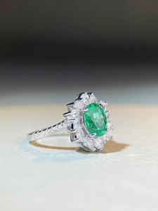 Macro shot of S925 sterling silver ring with emerald-green gemstone and halo petals