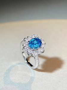 Macro shot of oval blue sapphire S925 silver ring with marquise zircon flower halo