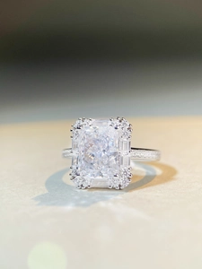 Macro shot of silver ring featuring radiant cut center stone with halo diamond setting