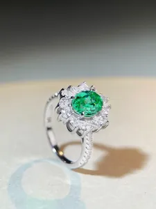 Macro shot of silver ring with emerald-cut green stone and sparkling zircon halo