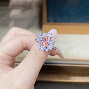 Close-up of flower shaped silver ring with pink center stone and marquise crystals