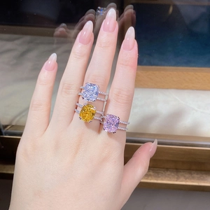 Close-up of three cushion cut rings in white, yellow, and pink colors with double halo stones