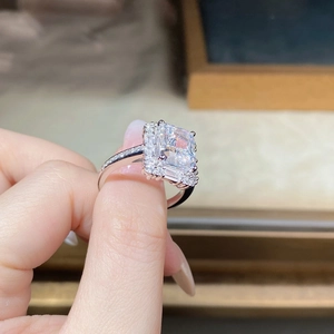 Detailed view of radiant cut rectangular gemstone ring with diamond halo on finger