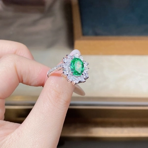 Macro detail of silver floral ring with green oval main stone and petal zircon clusters