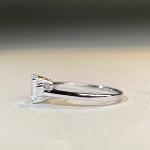 Detailed side view of silver ring with emerald cut moissanite in a four-prong setting